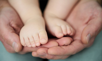 Obraz na płótnie Canvas Baby's feet and the hands of an adult.