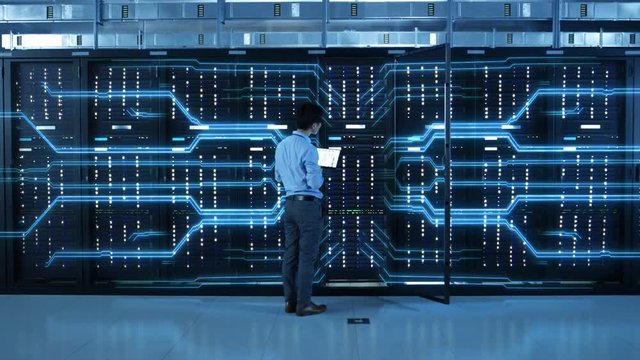 IT Specialist Standing In front of Server Racks with Laptop, He Activates Data Center with a Touch Gesture. Animated Concept of Digitalization of Information: Network of Lines Spreading Symmetrically