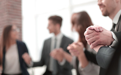 Business group in a circle holding hands indoors