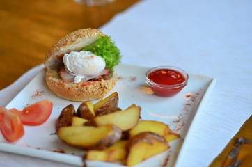 fried potatoes sliced with burger and poached egg with sauce