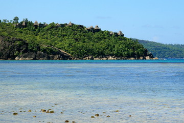 lagoon with clear blue water, tropical greenery and rocks with beach