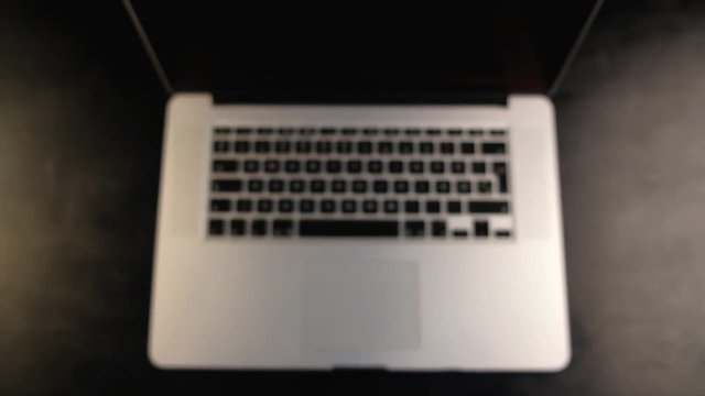Close-up of man hands showing thumb up or like gesture with laptop on black background.