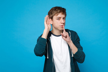 Curious young man saying hush be quiet with finger on lips shhh gesture, eavesdrop and hearing...