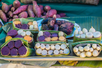 Grilled organic sweet potatoes for sale at the local fresh market with banana leave packing. 