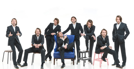 Obraz premium The eight identical handsome men in black suits differently pose on a white background, brutal man with long curly hairs, white shirts, business man, very stylish, blue leather chair, twins