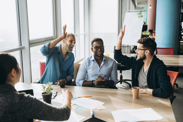 Work colleagues gathered around the table in positive mood to discuss working moments during the work process