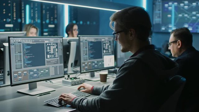 Team of IT Programers Working on Desktop Computers in Data Center Control Room. Young Professionals Writing on Sophisticated Programming Code Language