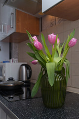 Pink tulips in the green vase on the kitchen table