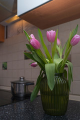 Pink tulips in the green vase on the kitchen table