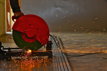 The steel worker use red circular saw cutting cube steel with split fire