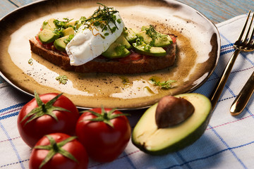 Fresh Avocado Toast and Poached Egg with Baked Tomatoes, close-up