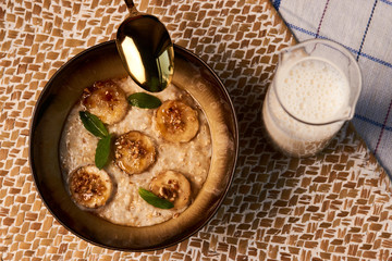 Breakfast oatmeal porridge bowl with banana and caramel, close-up