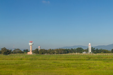 Fototapeta na wymiar Airplane control tower on the green grass field with blue sky background at Chiang Rai International Airport, Thailand.