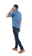 Back view of man walking with a mobile phone.