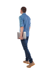 Back view of a walking man with a laptop.