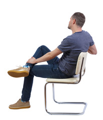 Side view of a man sitting on a chair.