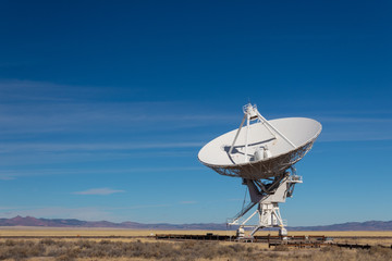 Very Large Array Distant view of radio antenna against a blue sky, gold fields and purple mountains, horizontal aspect