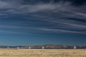 Very Large Array line of radio astronomy observatory telescopes in the New Mexico desert, copy space in blue sky, horizontal aspect