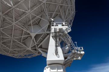 Very Large Array upright and trusses under radio astronomy observatory dish against blue sky,...