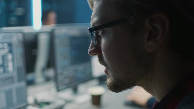 Smart Male IT Programer Working on Desktop Computer in Data Center Technical System Control Room. Team of Young Professionals Programming in Coding Language