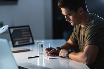 Fototapeta premium Young US army soldier writing letter at the desk.