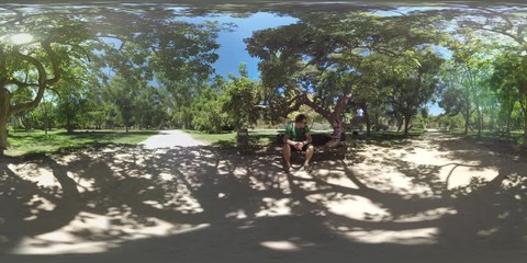 VALENCIA, SPAIN - JULY 15 2016: 360 VR video. Father and son (with model release) having a rest in one of the largest urban parks Turia Gardens. Child trying to climb a tree, dad helps him. Green