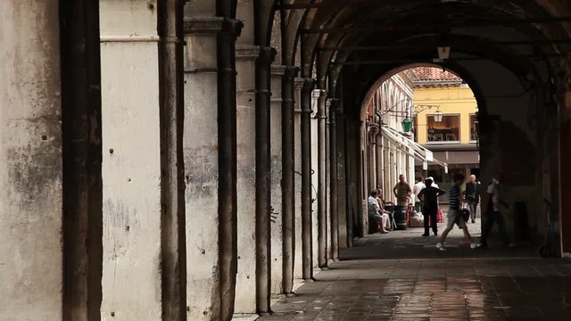 WS Pedestrians walking under portico in distance / Venice, Italy