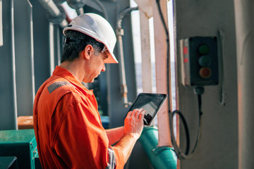 Marine chief officer or captain on deck of vessel or ship watching digital tablet. Internet and...