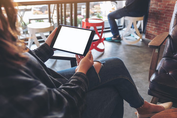 Mockup image of a woman holding black tablet pc with blank white screen horizontally while sitting in cafe