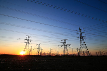 Fototapeta premium A high-voltage tower in the setting sun against the sky
