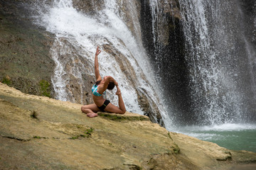 Filipino girl yoga posing at tropical waterfall 