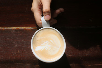 hand holding a cup of coffee on black background