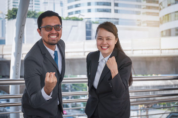 Fototapeta premium Two business people smile in an urban environment that lifted his hand and delighted with success