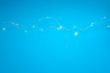 Christmas lighting and New Year template concept theme with close up on LED lights connected by thin copper wire isolated on blue background with copy space