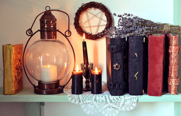 Witch shelf with magic books, old lamp, black candles and lavender herbs. Magic gothic ritual. Wicca, esoteric, divination and occult background with vintage objects