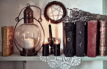 Magic book, burning black candles, old-fashioned lamp and pentagram. Magic gothic ritual. Wicca, esoteric, divination and occult background with vintage objects