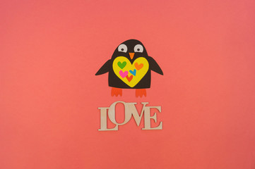 word love of wood and paper penguin. Coral background.