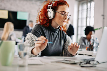 Female freelancer enjoying in good music while working in the office.