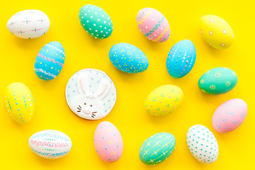 Colorful Easter eggs background and gingerbread on yellow top view