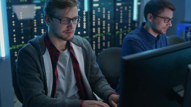 Team of Young IT Programers Working on Desktop Computers in Data Center System Control Room. Displays Show Concept: Software Development / Code Writing / Database Architecture. Technical Department