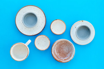 Obraz na płótnie Canvas Kitchen concept. Crockery kit. Empty ceramic plates and mugs on blue background top view