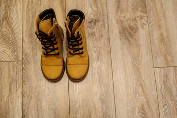 top view of a pair of yellow leather child shoes on a brown floor