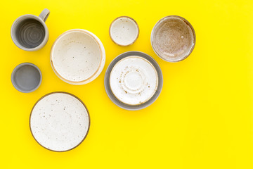 Ceramic tableware pattern. Empty plates and mugs on yellow background top view copy space