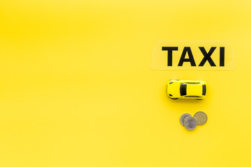 Taxi operator concept. Chip service. Sign taxi ner car toy and coins on yellow background top view copy space