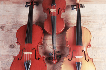 Fototapeta na wymiar Three violins on wooden texture