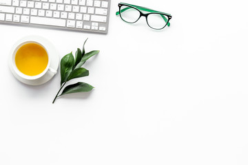 Spring inspiration. Office work desk with computer keyboard, glasses, fresh green spring leaves on white background top view copy space