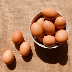 Bowl of eggs and 3 eggs on brown sack background 