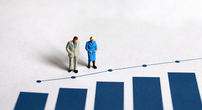 A miniature older people standing on a bar graph.