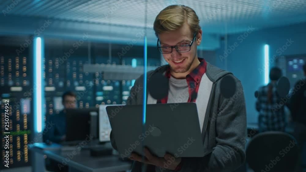 Leinwandbilder portrait of a smart focused young man wearing glasses holds laptop. in the background technical depa
