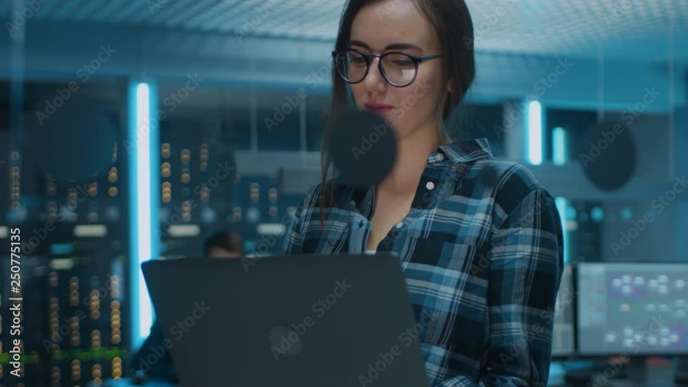 Poster portrait of a smart focused young woman wearing glasses holds laptop. in the background technical de